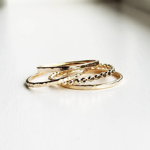 a stack of different gold band style rings on a white background