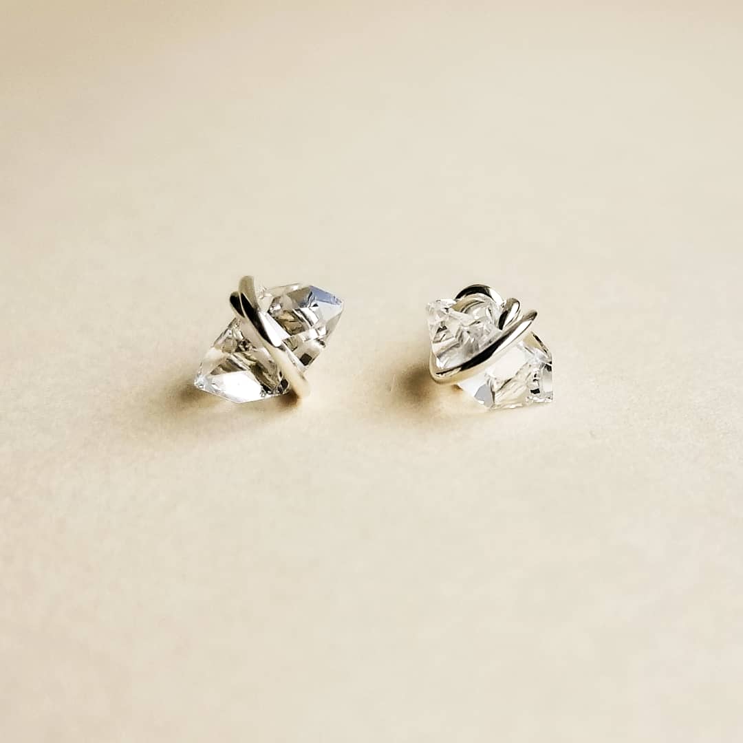 a set of small herkimer diamond stud earrings with silver metal on a white background