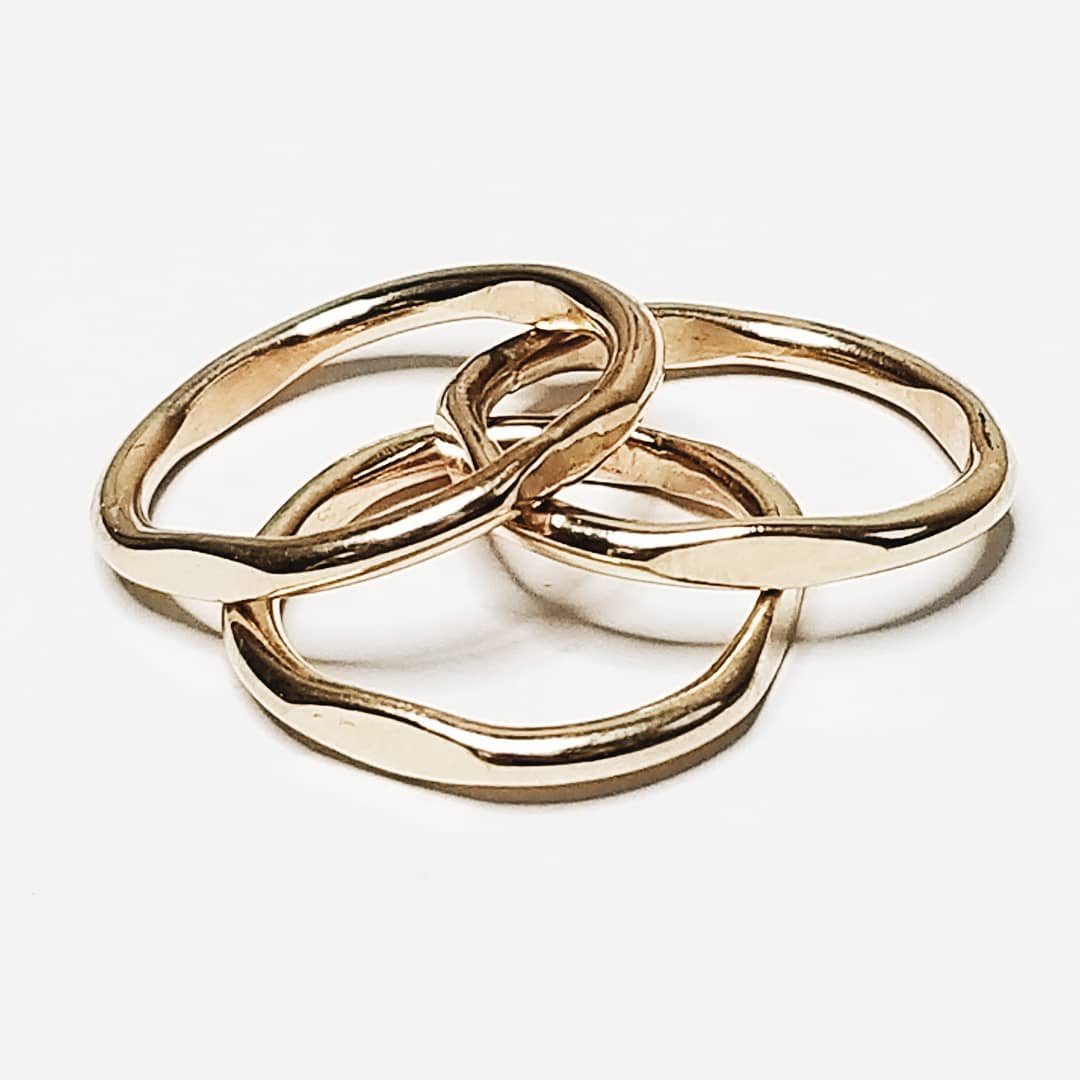 three simple gold rings stacked on a white background
