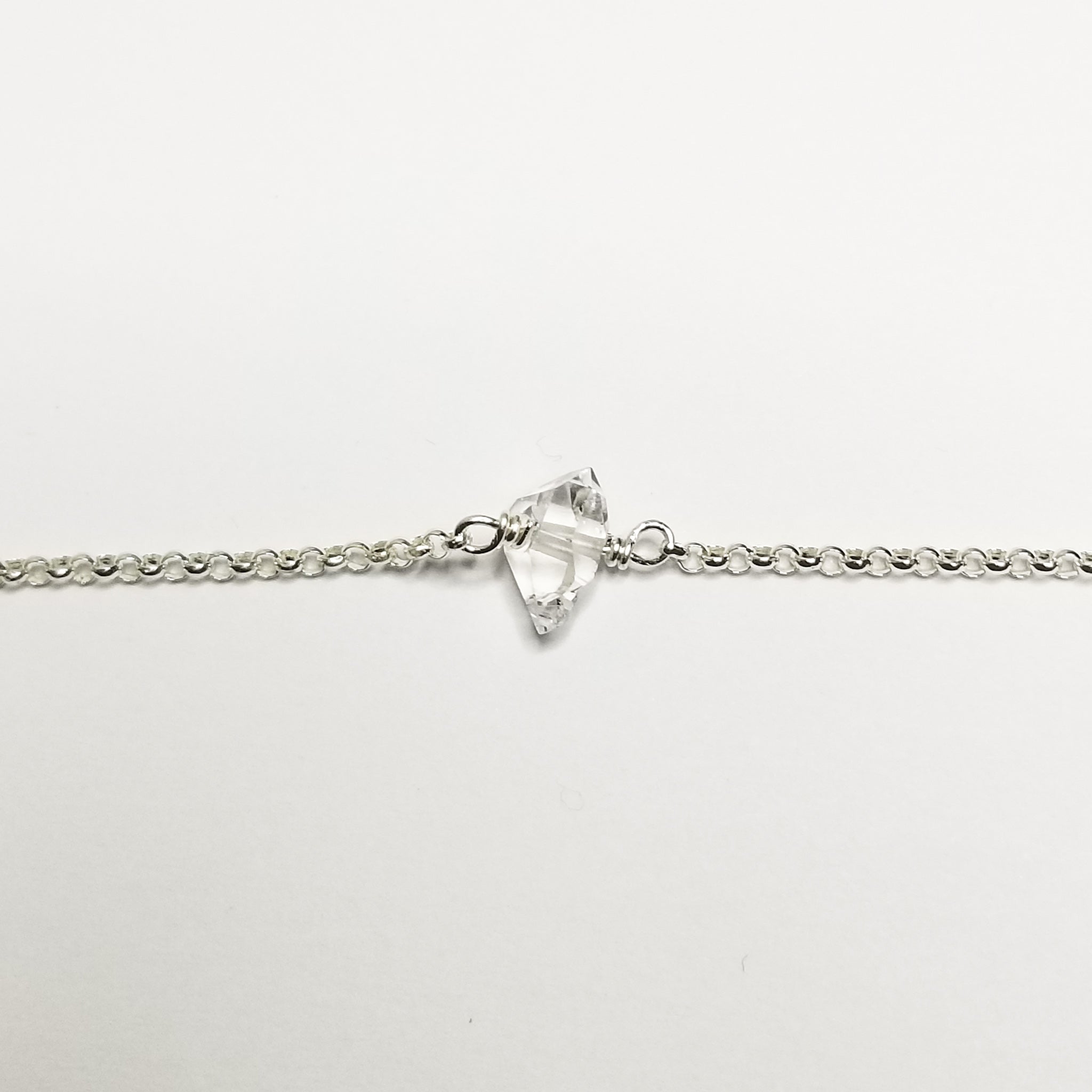 a herkimer diamond on a silver chain with a white background