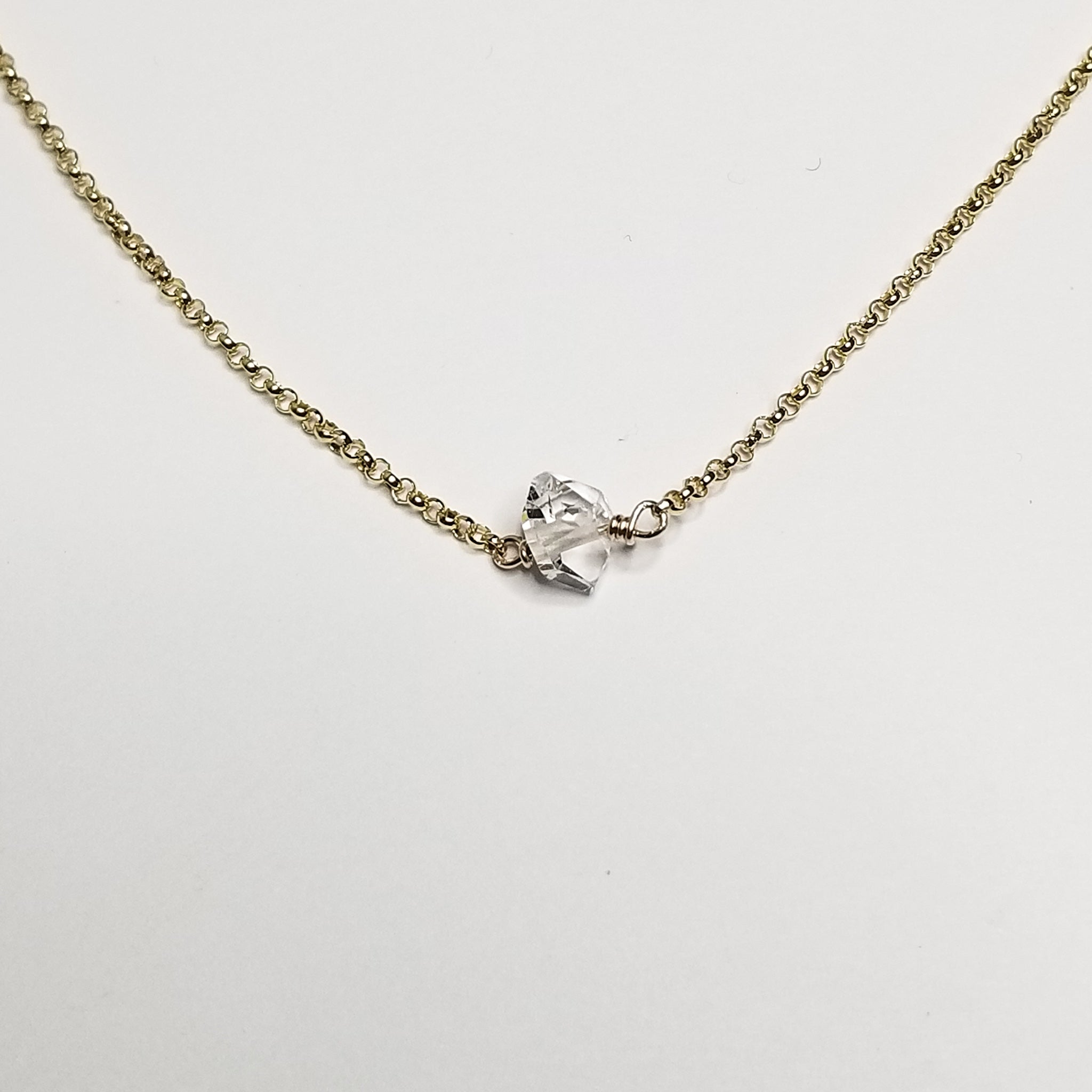 a herkimer diamond on a yellow gold chain with a white background