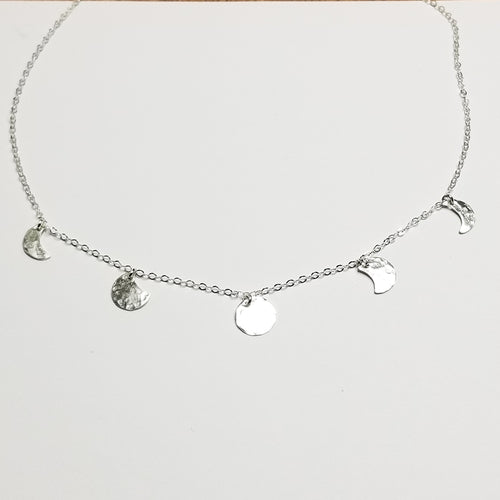 a silver chain necklace with small silver moon pendants showing the moon phase on a white background 