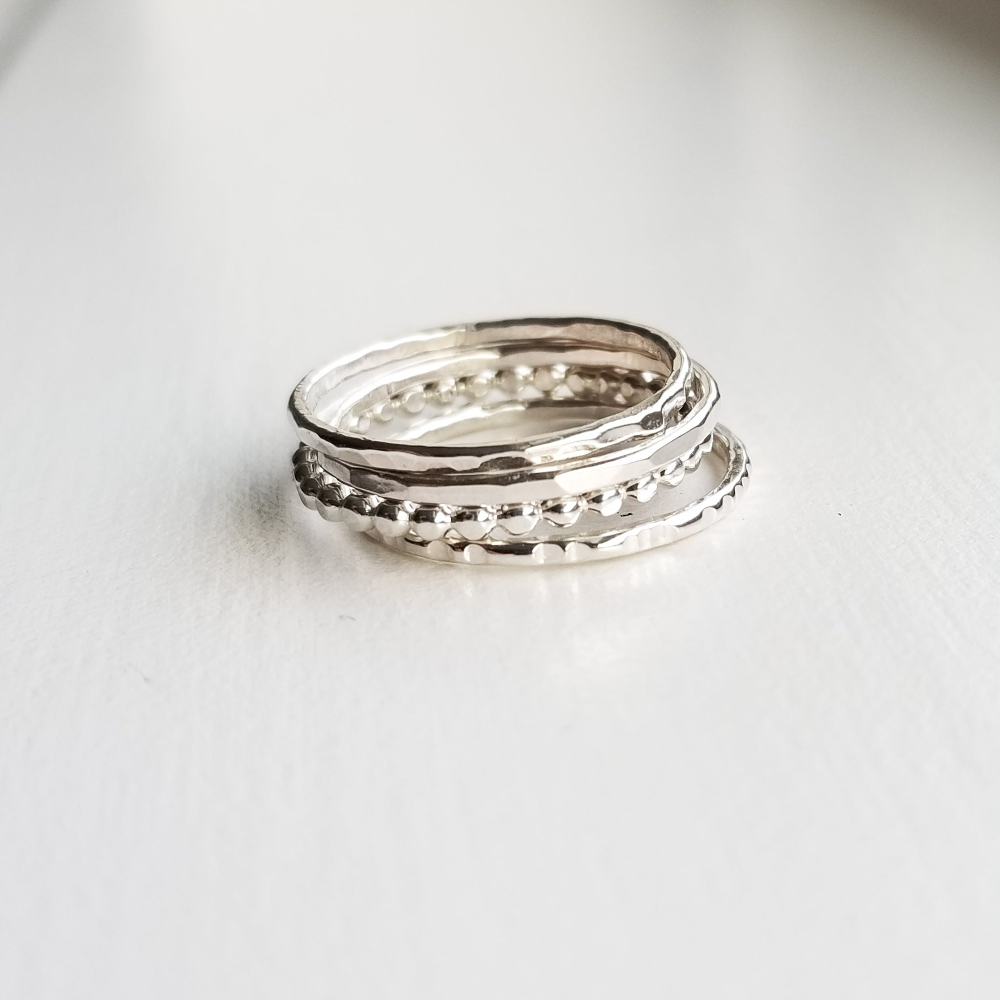 a stack of various silver band style rings on a white background