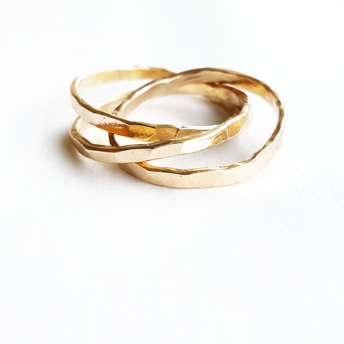 a set of intertwined gold band rings on a white background