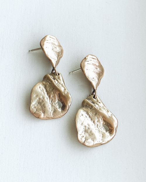 a set of dangly bronze sea shell stud earrings on a white background