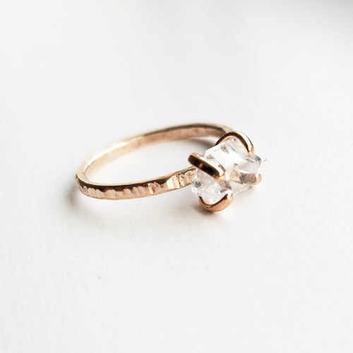 a gold claw style ring with a herkimer diamond on a white background