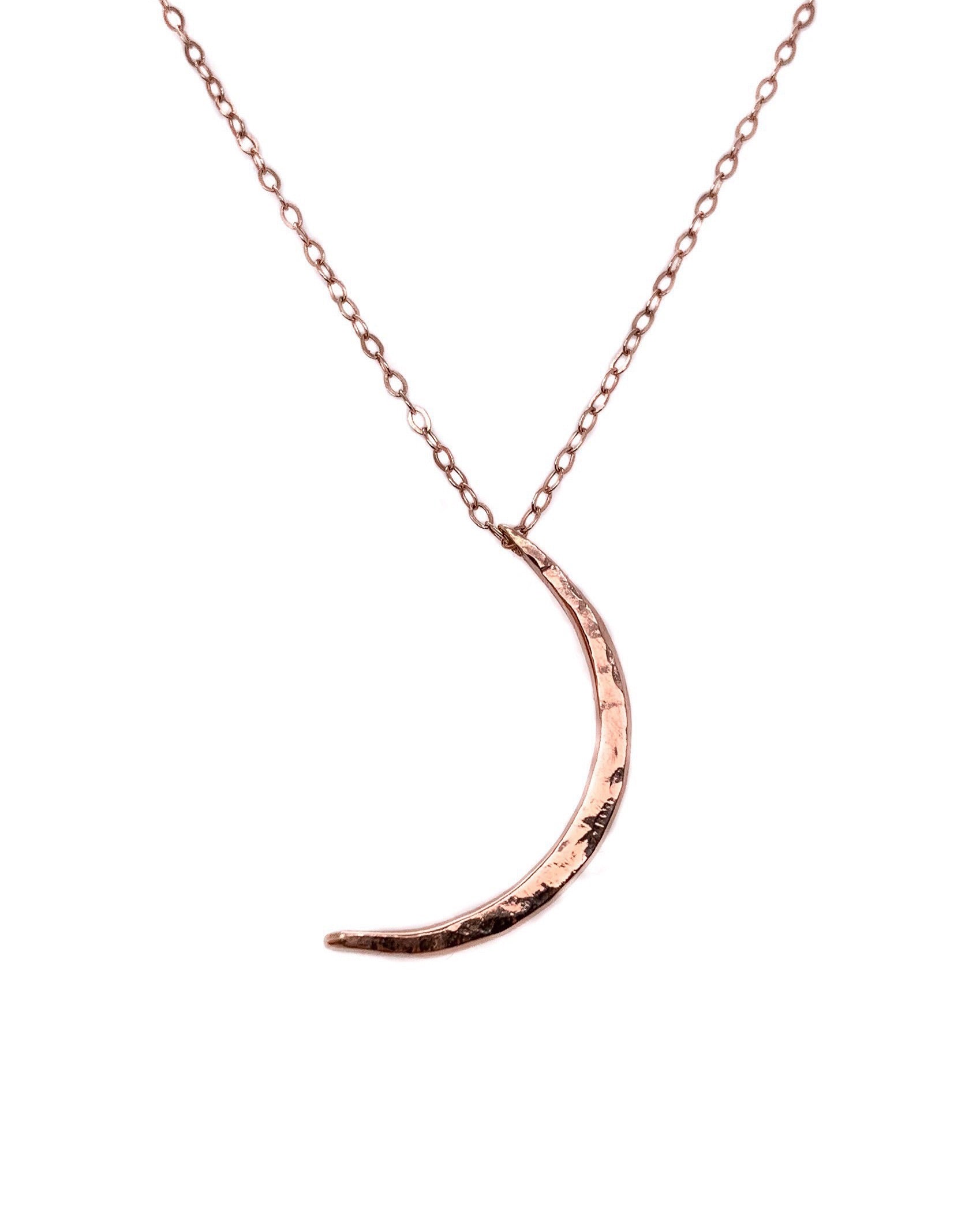 a crescent moon shaped rose gold pendant on a rose gold chain with a white background