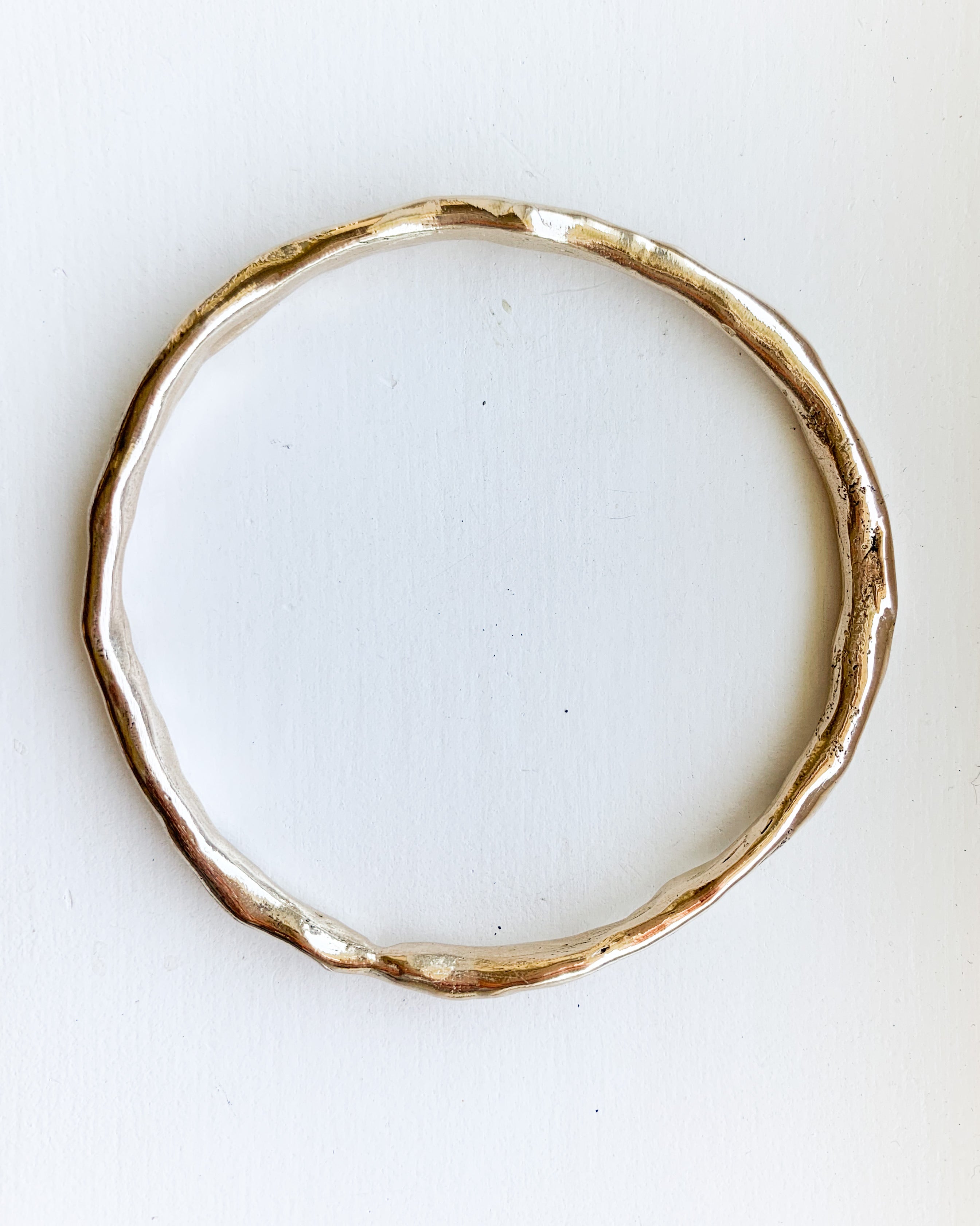 a hand formed bronze bangle bracelet shown on a white background