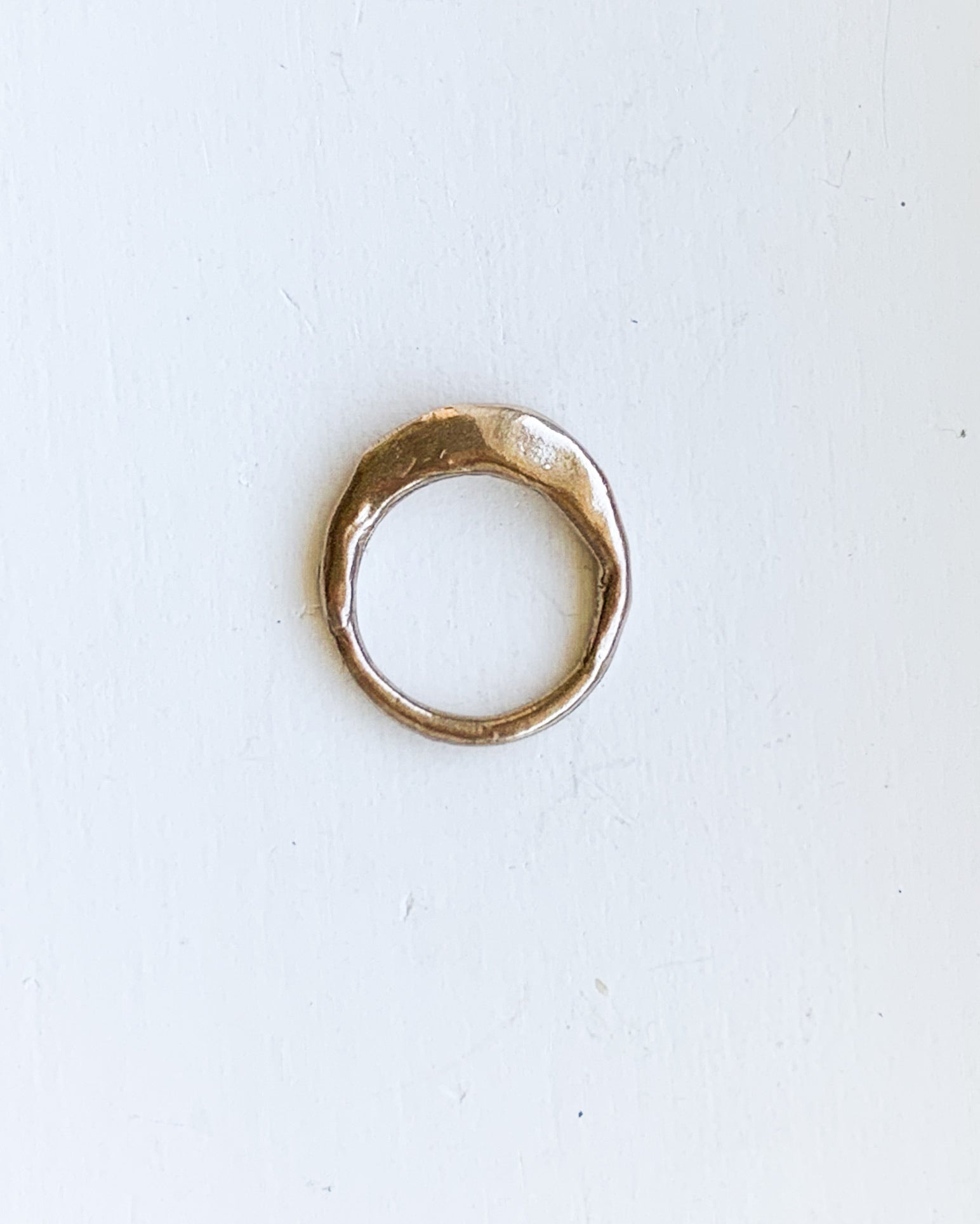 a hand formed bronze ring made from wax cast in metal on a white background