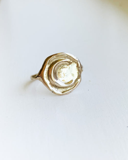a hand formed bronze moon ring on a white background