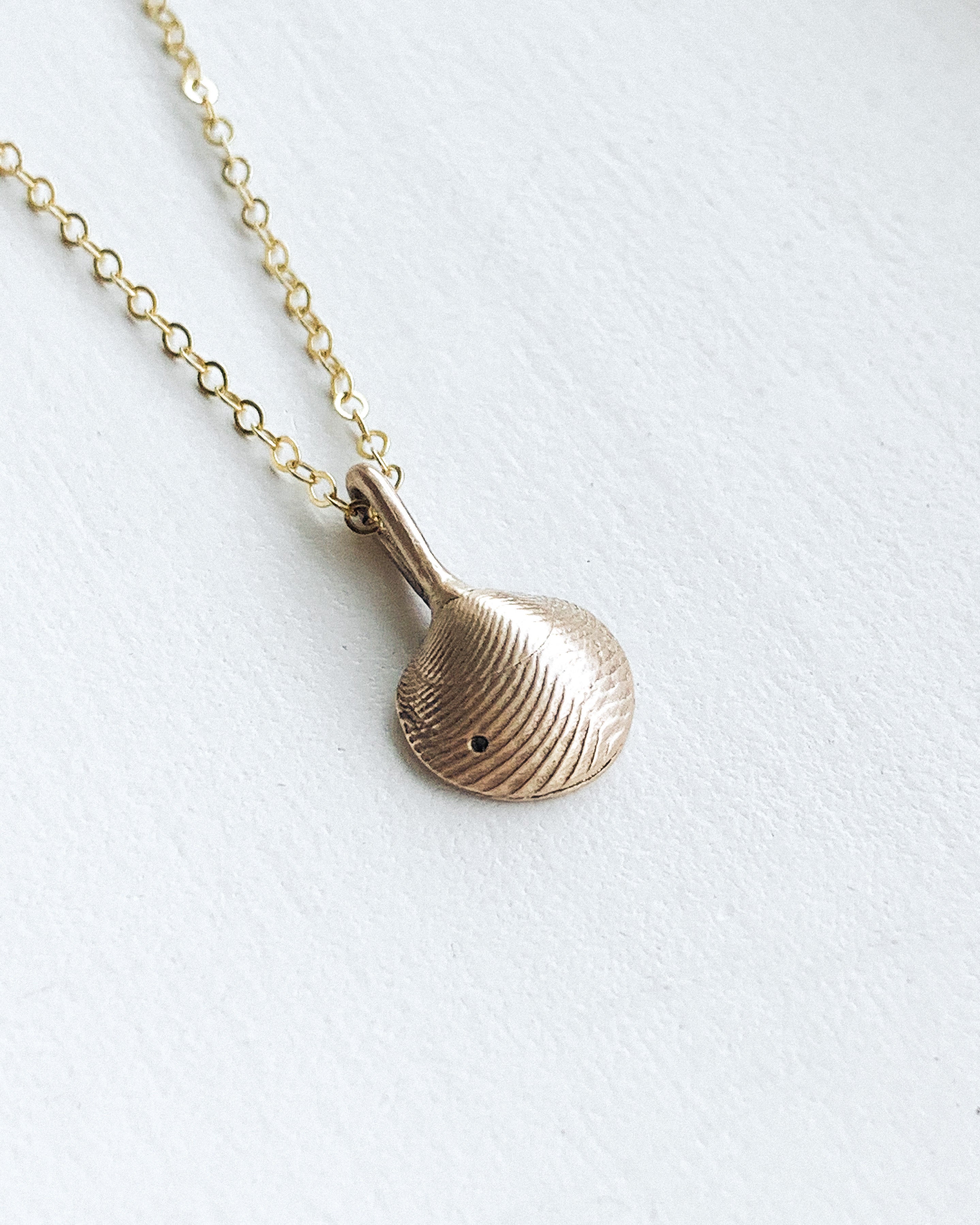 small bronze clamshell pendant with a bronze chain shown on a white background