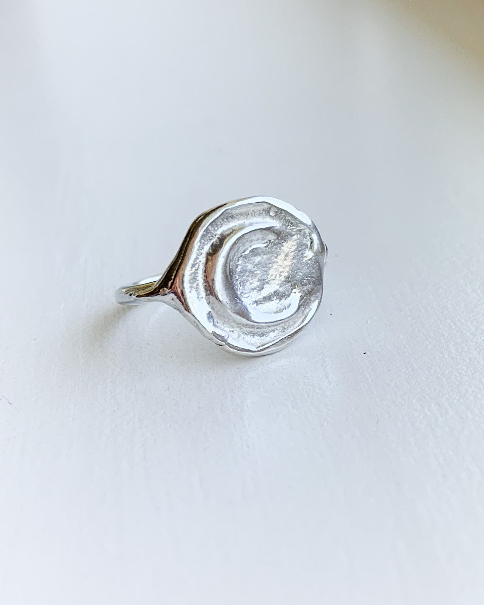 a hand formed silver moon ring on a white background