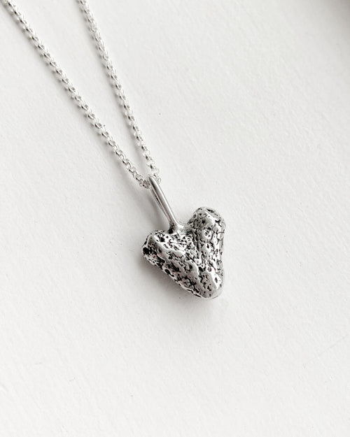 small silver coral heart pendant on a silver chain with a white background