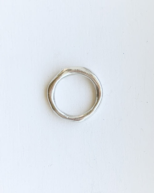 a hand formed silver band ring shown on a white background