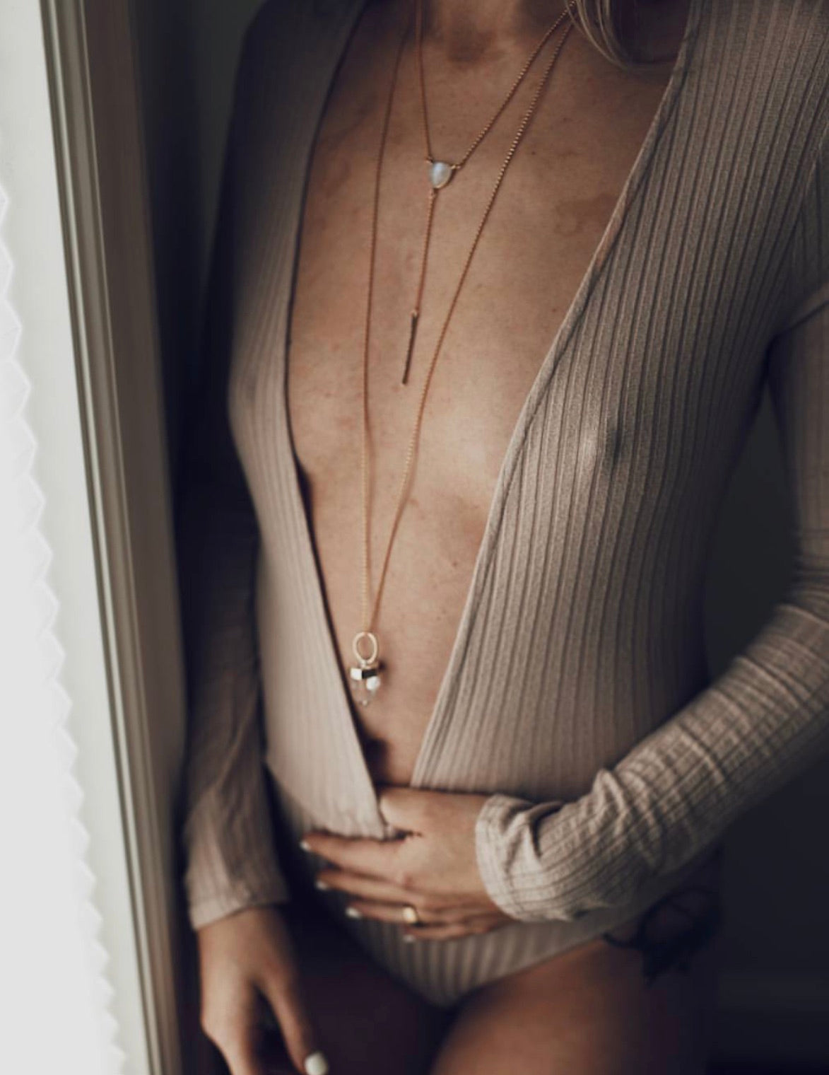 girl in a ribbed bodysuit with a deep v-neck bodysuit with long gold jewelry and crystal pendants