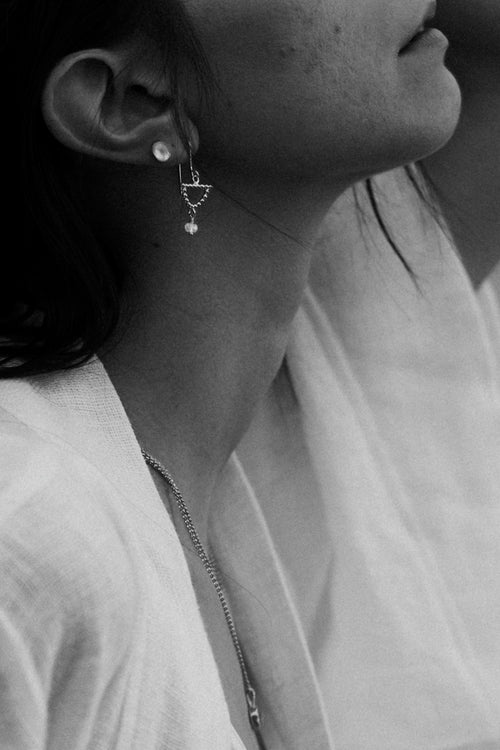 a black and white side profile of a woman wearing dangly earrrings and a white linen robe